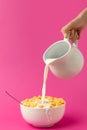 Cropped shot of hand holding jug and pouring milk into bowl with corn flakes Royalty Free Stock Photo