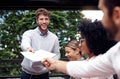 Please take one and pass it down. Cropped shot of a handsome young businessman standing and passing out documents to his Royalty Free Stock Photo