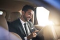 Finding success while on the road. Cropped shot of a handsome young businessman using a tablet while on his morning Royalty Free Stock Photo