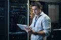 Checking the network status. Cropped shot of a handsome young male programmer working on a tablet in a server room.