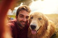 Smile, boy. Cropped shot of a handsome young man and his dog taking selfies by a lake in the park. Royalty Free Stock Photo