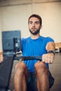 Serious about personal fitness. Cropped shot of a handsome young man working out on a rowing machine in the gym.