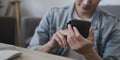 Cropped shot happy asian man sitting on couch and using smart phone