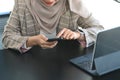 Cropped shot of happy muslim woman using mobile phone at her workplace. Royalty Free Stock Photo