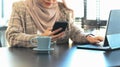 Cropped shot of happy muslim woman using smart phone while sitting in her office. Royalty Free Stock Photo
