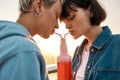 Cropped shot of happy young lesbian couple drinking from one glass bottle with the straw, Two girls enjoying cold Royalty Free Stock Photo