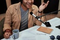 Cropped shot of happy young male radio host smiling, having cup of tea while broadcasting in studio using microphone and Royalty Free Stock Photo