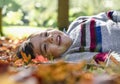 Cropped shot of kid boy laying down on leaves falling under the tree in sunny day ,Child having fun lying on autumn leaves and Royalty Free Stock Photo