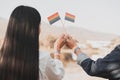 Cropped shot of LGBT lesbian couple hands holding a rainbow pride flag at sunset. LGBT rights concept