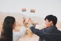 Cropped shot of LGBT lesbian couple hands holding a rainbow pride flag at sunset. LGBT rights concept