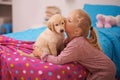 Kisses for her new friend. A cropped shot of a little girl kissing her puppy while it sits on her bed. Royalty Free Stock Photo