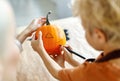 Cropped shot of little kid with mom preparing for holiday Halloween, making jack-o-lantern Royalty Free Stock Photo