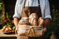 Cropped shot of male bakery owner or employee holding freshly baked wheat bread loaf packed in a craft paper bag. High Royalty Free Stock Photo