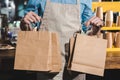 cropped shot of male barista in apron holding paper bags