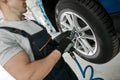 Cropped shot of male mechanic screwing or unscrewing car wheel of lifted automobile by pneumatic wrench at auto repair Royalty Free Stock Photo