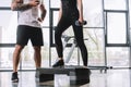 cropped shot of male personal trainer with timer and young sportswoman doing step aerobics exercise with dumbbells at gym Royalty Free Stock Photo