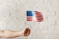 cropped shot of man holding american flagpole against white brick wall Royalty Free Stock Photo