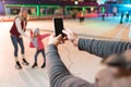 cropped shot of man holding smartphone with blank screen and photographing family skating Royalty Free Stock Photo