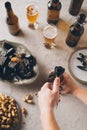 cropped shot of man opening bottle of cold beer at tabletop with peanuts Royalty Free Stock Photo