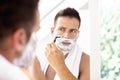 Handsome man shaving his beard while standing in front of a mirror Royalty Free Stock Photo