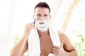 Handsome man shaving his beard while standing in front of a mirror Royalty Free Stock Photo
