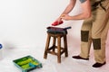 cropped shot of man in working overall pouring paint from bottle into roller tray