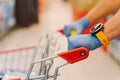 Cropped shot of mans hands in rubber gloves on handle of shopping cart against blurred supermarket background. Shopping,