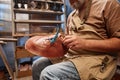 Cropped shot of mature male manufacturer in apron holding upper part of boot