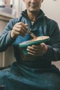 cropped shot of mature shoemaker holding boot workpiece and working with sole at his