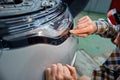 Cropped shot of mechanic applying protective film on headlight Royalty Free Stock Photo