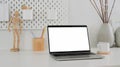 Cropped shot of modern designer workspace with mock up laptop, wooden figure, pencils and ceramic vase on white table Royalty Free Stock Photo