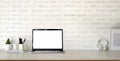 Cropped shot of modern stylish workplace with open blank screen laptop computer and office supplies on marble desk and brick wall Royalty Free Stock Photo