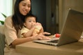 Cropped shot mother working with laptop at home with little baby son. Motherhood and child care concept Royalty Free Stock Photo