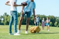 cropped shot of multiethnic boys playing with rugby ball while classmates walking behind