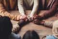 cropped shot of multiethnic friends holding hands while sitting in cafe, diversity and people holding hands by a table at a group