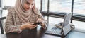 Cropped shot of muslim business woman in Brown hijab and casual wear sitting and using smartphone