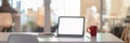 Cropped shot of office desk with blank screen laptop, notebooks and coffee cup in glass partition room Royalty Free Stock Photo