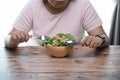 Cropped shot of overweight woman is tired of diet restrictions eating green salad.