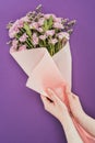 cropped shot of person holding beautiful floral bouquet wrapped in pink craft paper Royalty Free Stock Photo