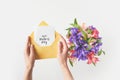 cropped shot of person holding envelope with happy mothers day greeting card and beautiful bouquet of flowers on grey Royalty Free Stock Photo