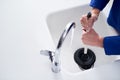 Keeping the drains clean. Cropped shot of a plumber. unblocking a drain with a plunger.