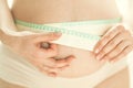 Cropped shot of pregnant woman measuring herself with flexible ruler