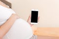 Cropped shot of pregnant woman showing smartphone with black screen in bed Royalty Free Stock Photo