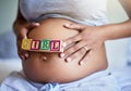 Getting the gift of a little girl. Cropped shot of a pregnant woman with wooden blocks on her belly that spell the word Royalty Free Stock Photo