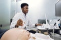 Cropped shot of a pregnant woman during ultrasound scanning, visiting her male African doctor obstetrician, using modern