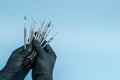 Cropped shot of professional dentist in black medical gloves with dental tools. Dental concept. Isolated on blue background Royalty Free Stock Photo