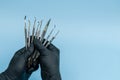 Cropped shot of professional dentist in black medical gloves with dental tools. Dental concept. Isolated on blue background Royalty Free Stock Photo