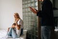 Cropped shot of scared mother and daughter hugging each other sitting on sofa while aggressive standing father angrily Royalty Free Stock Photo