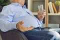 Senior patient taking prescribed medication with water sitting in an armchair at home Royalty Free Stock Photo