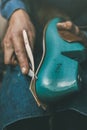 cropped shot of shoemaker cutting material with knife to size of